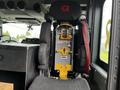 Interior view of a 2009 Spartan Gladiator fire truck showing a driver seat with a yellow safety harness and a black seat cover