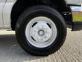 A close-up view of a white wheel and tire from a 2013 Ford Econoline with six bolt holes and a distinctive tread pattern