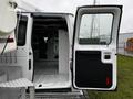 A white 2009 Ford Econoline van with the side door open revealing a spacious interior without seats or equipment