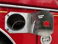 A shiny silver compartment door on a red fire truck with an open lid revealing a large circular opening inside and a label that reads "LINDY LOOP"
