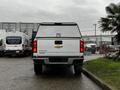 A white 2019 Chevrolet Colorado pickup truck viewed from the rear with a silver Chevrolet emblem on the tailgate and a cap over the truck bed