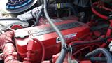 Close-up of a red Cummins engine with visible hoses and wiring in a 2011 Freightliner M2 Medium Duty