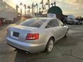 A silver 2006 Audi A6 with a sleek design and distinctive rear lights parked in a lot with other vehicles visible in the background