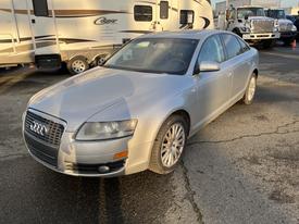 A silver 2006 Audi A6 parked with its front slightly turned showcasing its sleek design and five-spoke wheels