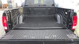 The bed of a 2017 RAM 1500 truck with a black plastic liner featuring grooves and side compartments