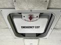 A ceiling-mounted emergency exit hatch labeled with instructions for operation and "EMERGENCY EXIT" displayed prominently