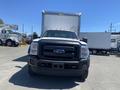 A 2015 Ford F-450 SD with a black front grille and orange roof lights is parked in the foreground facing the camera