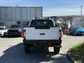 A white 2017 Ford F-350 SD with a black bed liner and ladder rack is parked, showcasing its rear view and tailgate with the Ford logo