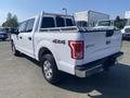 A white 2017 Ford F-150 truck with a 4x4 badge and a silver ladder rack in the bed is parked in a lot