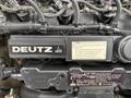 Close-up of a Deutz engine featuring ventilation pipes and warning labels prominently displayed on the black casing