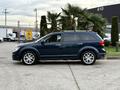 A blue 2013 Dodge Journey is parked with its side profile visible featuring sleek lines and alloy wheels