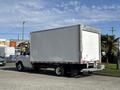 A 2023 Ford E-450 box truck with a white cargo area and a black chassis parked on a street
