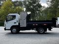 A 2015 Mitsubishi Fuso FE truck with a flatbed and a storage compartment attached to the side