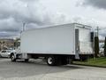 A 2017 Hino 338 truck with a boxy cargo area and a white exterior is parked diagonally with its rear doors open