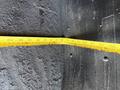 A close-up view of a yellow measuring tape extended across a textured surface, showing various inch measurements prominently displayed