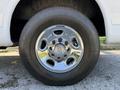 Close-up of a chrome wheel on a 2021 Chevrolet Express van with a Chevrolet logo in the center and a thick black tire showing tread details