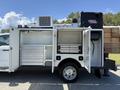 A white 2023 Ford F-550 with equipment compartments open featuring storage drawers and a generator on top