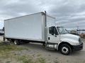 A 2014 International Durastar box truck with a white cargo area and a gray cab parked on a gravel surface