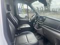 Interior view of a 2024 Ford Transit showcasing two black front seats and a dashboard with a touchscreen display and controls