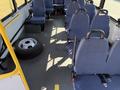 A 2017 Chevrolet Express interior showing blue seats arranged in rows with a spare tire on the floor near the side