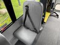 A gray seat with a safety strap inside a vehicle, designed for passenger use, featuring a padded cushion and a sturdy backrest