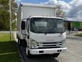 A white 2016 Isuzu NQR truck with a large box-style cargo area and an enclosed front cabin featuring side mirrors and orange marker lights on the roof