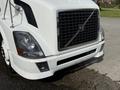A front view of a white 2012 Volvo VNL semi-truck showcasing its distinctive grille headlights and bumper design