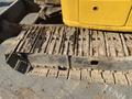 A close-up of the track and undercarriage of a yellow 2006 Komatsu PC55MR2 excavator showing wear and dirt accumulation
