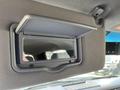 A mirror cover is open revealing a small rectangular mirror inside mounted on the sun visor of a 2014 Ford F-150