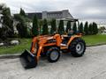 A 2001 Agco ST40 tractor with a front loader attachment, featuring orange paint and black wheels, parked on a concrete surface with a seat for the operator