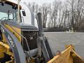 A 2011 John Deere 310SJ 4x4 Wheel Loader with an extended hoe and a 4-in-1 bucket positioned in the foreground