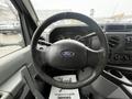 Steering wheel of a 2017 Ford Econoline with a Ford logo visible in the center and dashboard controls in the background