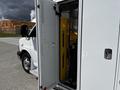 A 2013 Chevrolet Express with an open side door revealing a yellow wheelchair lift inside the cargo area