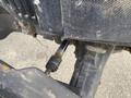 A close-up of a 2016 New Holland T475 tractor's front axle showing rusty components and a visible drive shaft connection
