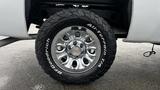 A chrome wheel with a large all-terrain tire mounted on a 2013 Chevrolet Silverado 1500