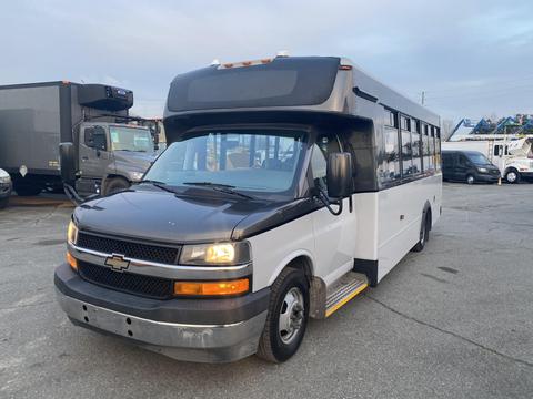 A 2017 Chevrolet Express van with a black front and white body featuring large windows and a low step at the entrance