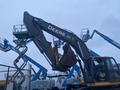 A 2014 John Deere 350G excavator with a large bucket and distinctive green and yellow branding positioned in an industrial setting