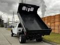 A 2019 Ford F-550 dump truck with its bed tilted upwards revealing a spacious cargo area