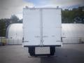 A white 2021 Mack MD truck with a large box-style cargo area and rear doors, viewed from the back