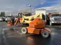 A 2012 JLG E400AJFN articulating boom lift with orange and yellow colors positioned on a parking lot surface