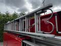 A 1991 Sutphen Deluge fire truck with a silver metal ladder mounted on top featuring several rungs and a distinctive curved design