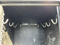 Interior view of a storage compartment with several metal hooks mounted on the back wall and a black base with signs of wear