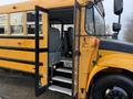 A 2013 International 4300 school bus with its doors open revealing empty seats and steps leading inside