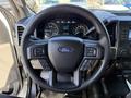 Steering wheel of a 2018 Ford F-150 featuring the Ford logo and various controls for navigation and audio settings