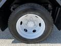 Close-up of a white wheel mounted on a black truck with six lug nuts visible on the wheel hub