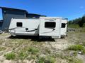 A 2014 Starcraft Launch 24RLS travel trailer parked on a gravel surface with its pop-out section extended