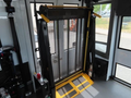 A wheelchair lift inside a vehicle with a metal platform and mesh protective screen designed for accessibility