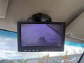 A monitor displaying a rearview camera feed showing a pathway behind a vehicle