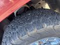 Close-up of a rugged tire with deep treads mounted on a rim showcasing intricate designs typical of a 2011 Chevrolet Avalanche