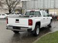 A white 2015 GMC Sierra 1500 pickup truck with a bed rack and visible GMC branding on the tailgate